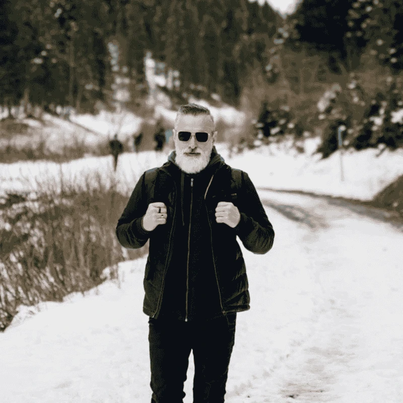 Un hombre con barba caminando por un camino nevado